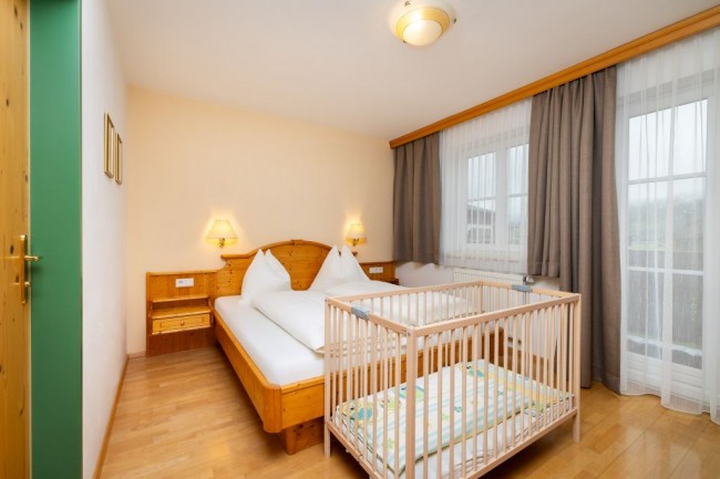 Schlafzimmer mit Kinderbett und Balkon